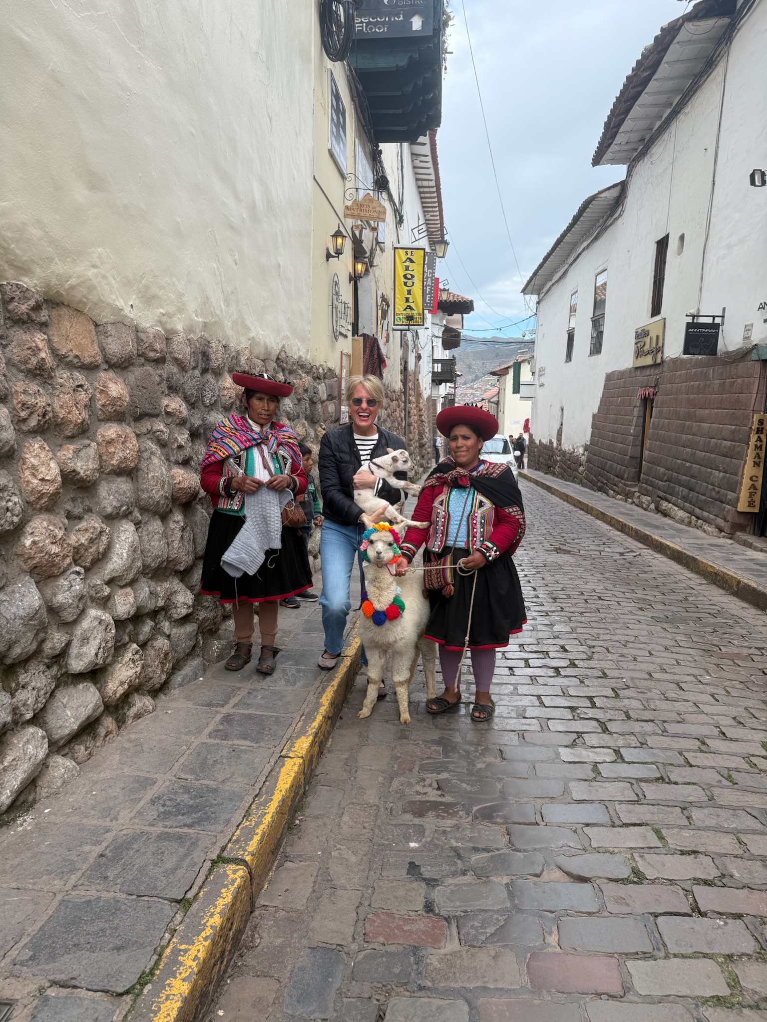 Woman standing in between two Peruvian women wearing traditional attire
