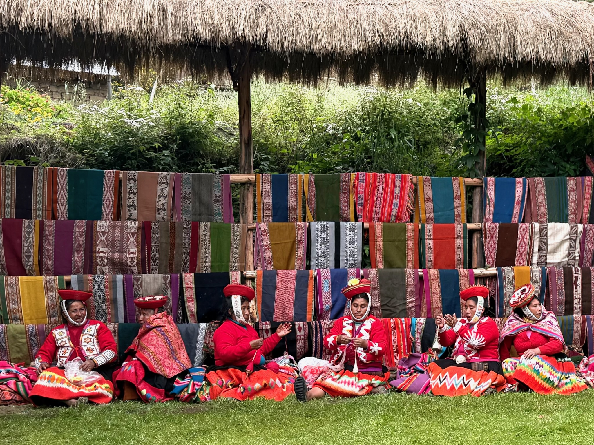 Group of Peruvian women creating textiles under a hut
