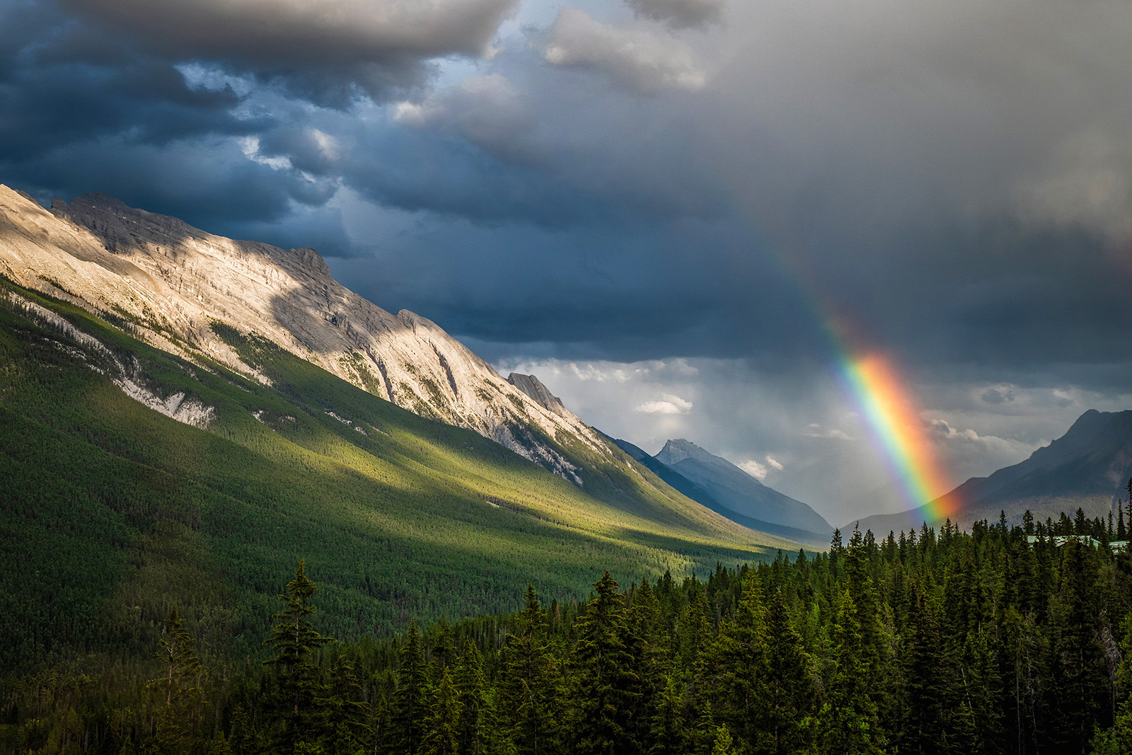 Rainbow under heavy clouds over mountain