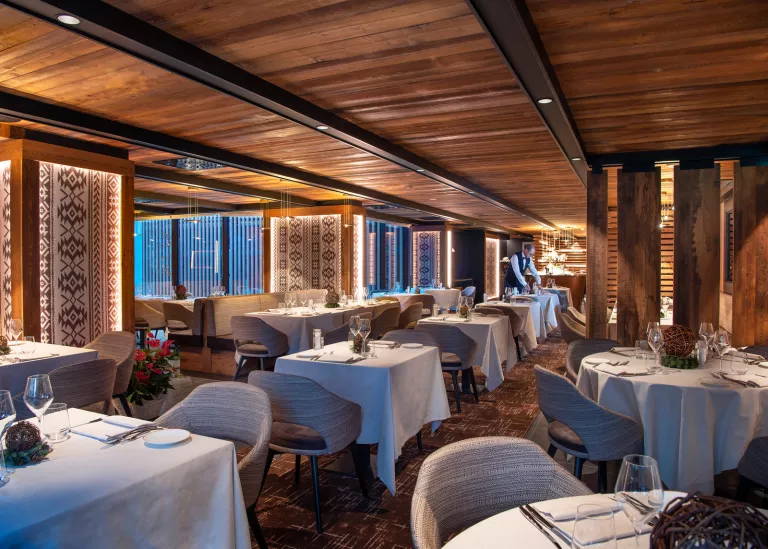 Indoor dining hall in a wooden lodge-style room, with gray cushioned chairs