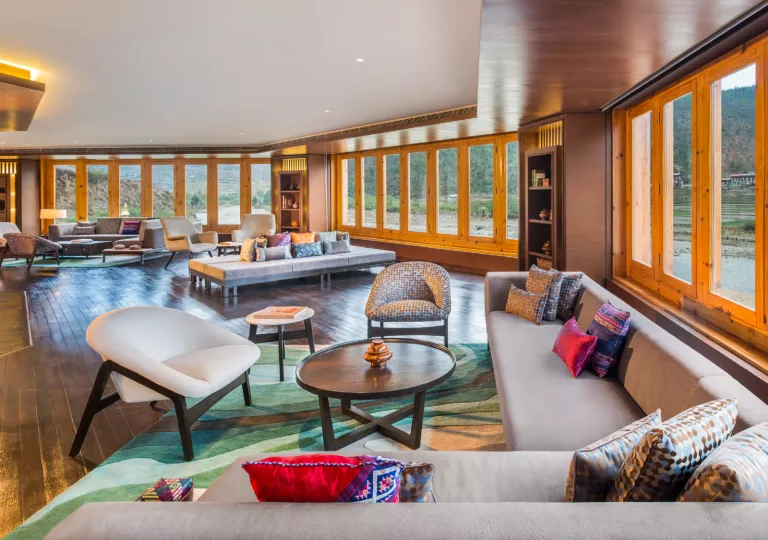 Lounge with gray sofas surrounded by large windows with wooden trim