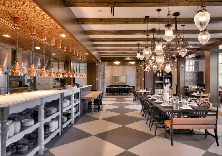 Dining hall with large light fixtures and a counter on the left full of black and white plates
