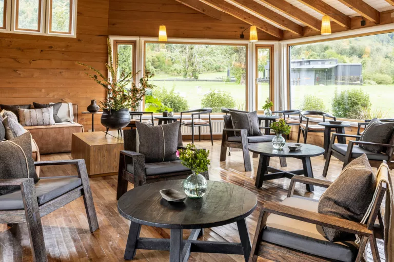 Seating area in a wooden room, with black painted chairs and tables