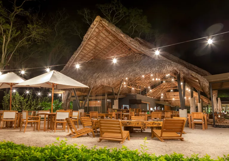 Outdoor hut with wooden chairs and tables on the sand
