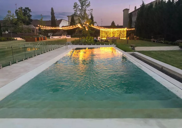 Outdoor pool surrounded by open grass areas