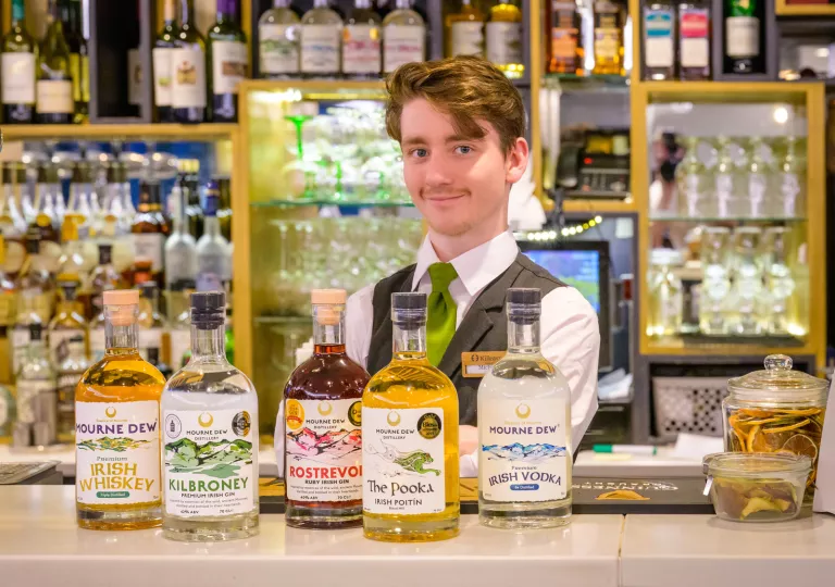 Bartender with multiple bottles of Irish whiskey on the counter