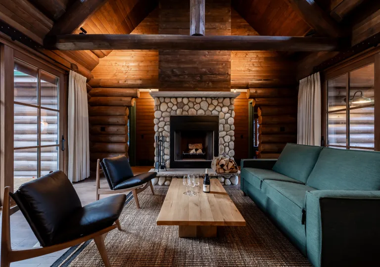 Indoor lodge lobby with black and green sofas surrounding a stone fireplace