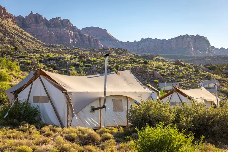 Large, luxury hut tents in the middle of a valley with canyons in the background