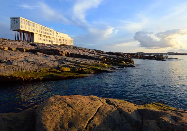 Long white building on large cliffs next to a body of water
