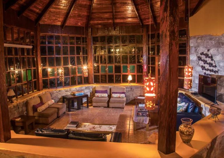Indoor view of wooden lodge wit an open seating area, and dangling red light fixtures