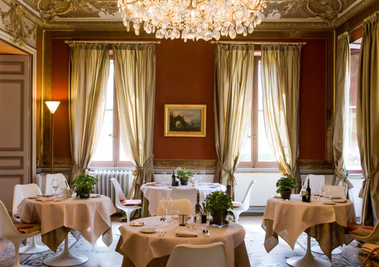 Dining area with 4 circular tables and a chandelier on the ceiling