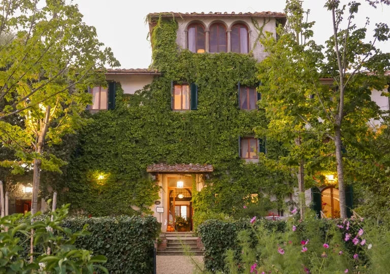 Exterior view of two-story building covered in plants and moss