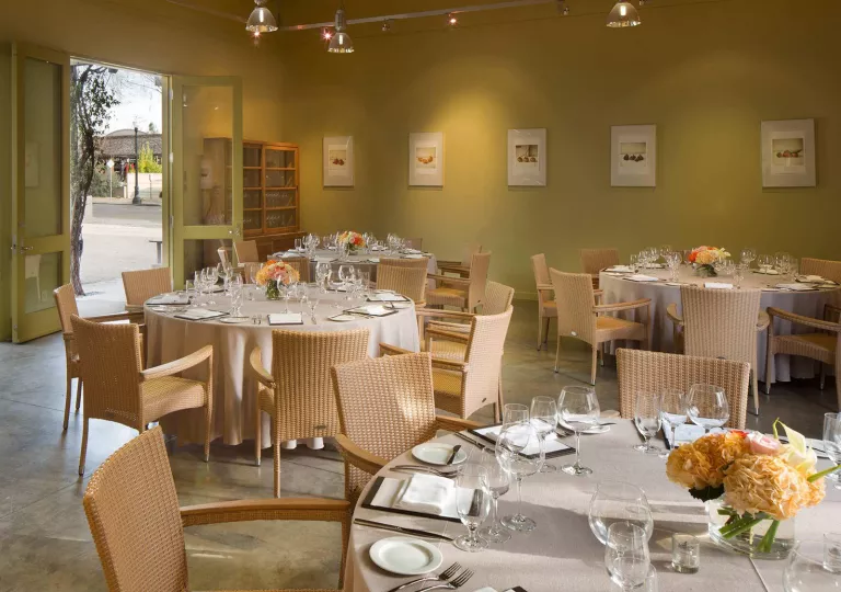 Dining room with tabls and glasses on wine with the door open on the left