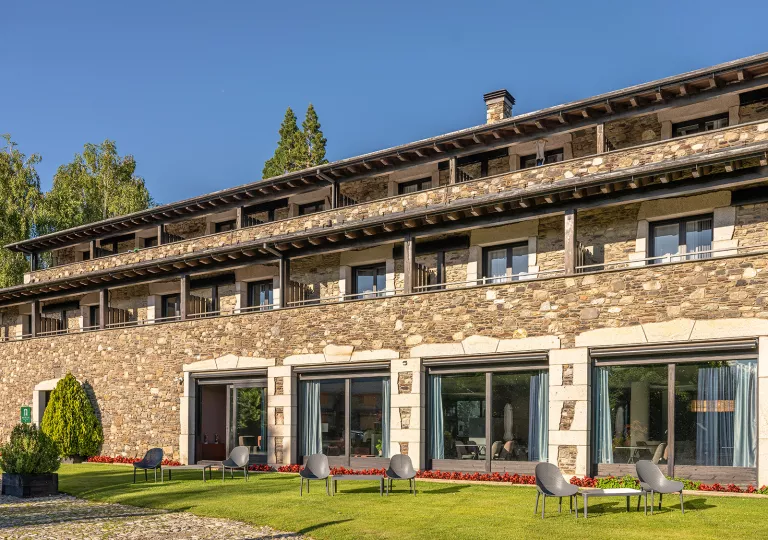 Exterior view of stone building with large windows and a grass area in front