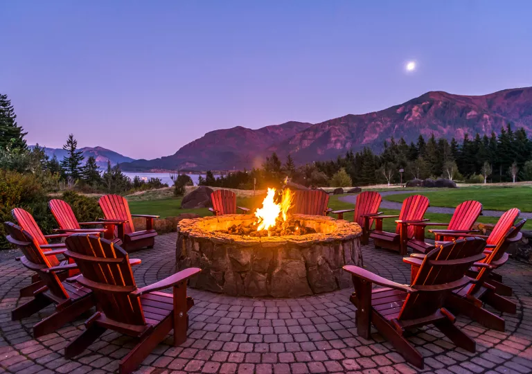 Outdoor stone firepit with red chairs surrounding it