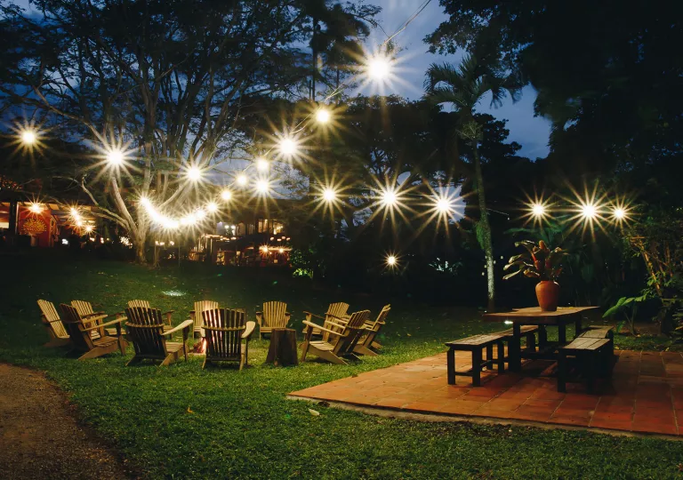 Outdoor patio with with wooden chairs around an open fire pit