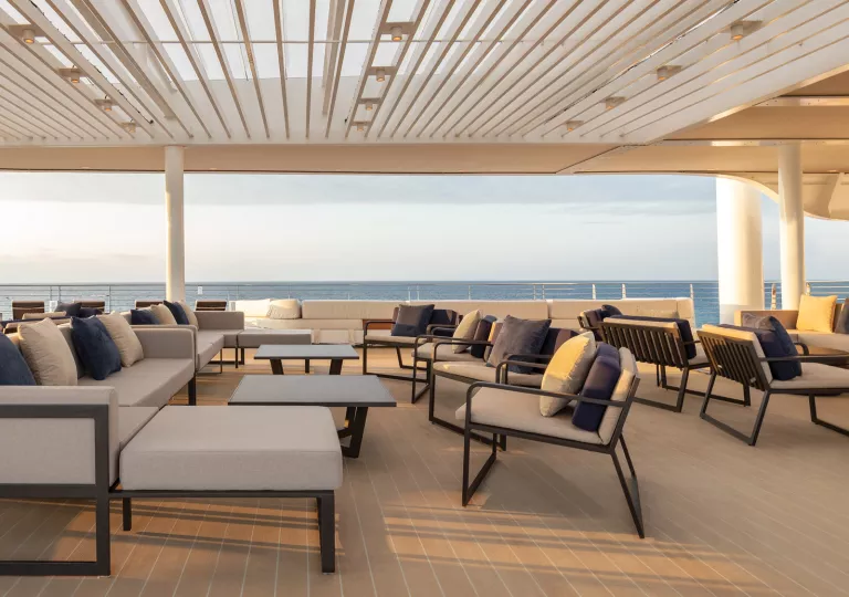 Cruise hip's outdoor patio with cushioned chairs, looking out towards the ocean