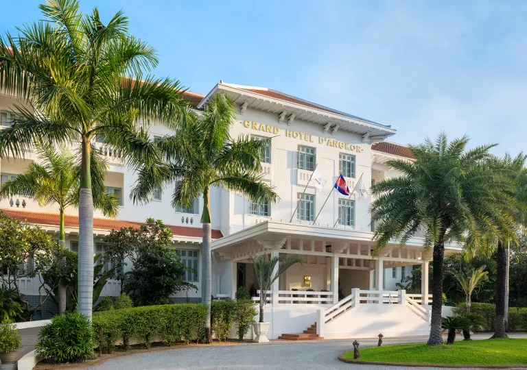 Exterior view of white hotel building with flags waving in front