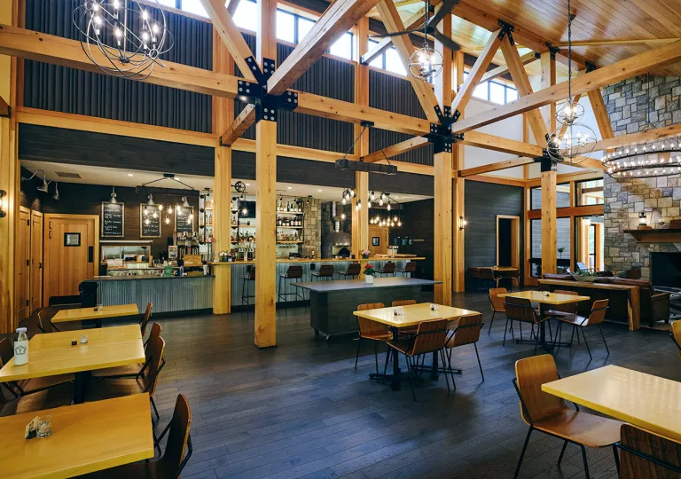 Restaurant and bar with wooden tables along the walls and large wooden pillars