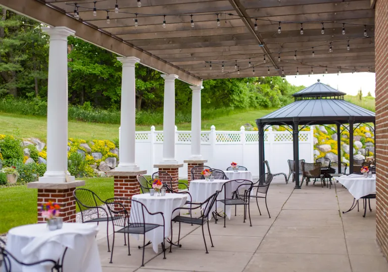 Outdoor patio with white dining tables and black, metal chairs