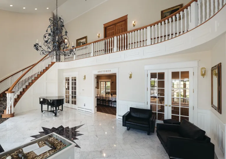 Large lobby white room with black sofas and a piano in the corner