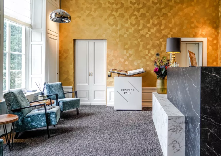 Hotel lobby with blue cushioned chairs and a marble counter to the right