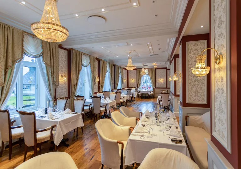Dining hall with tables with linens and cushioned chairs