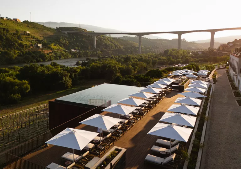 Outdoor patio with a pool, reclining chairs and a view of a tall bridge