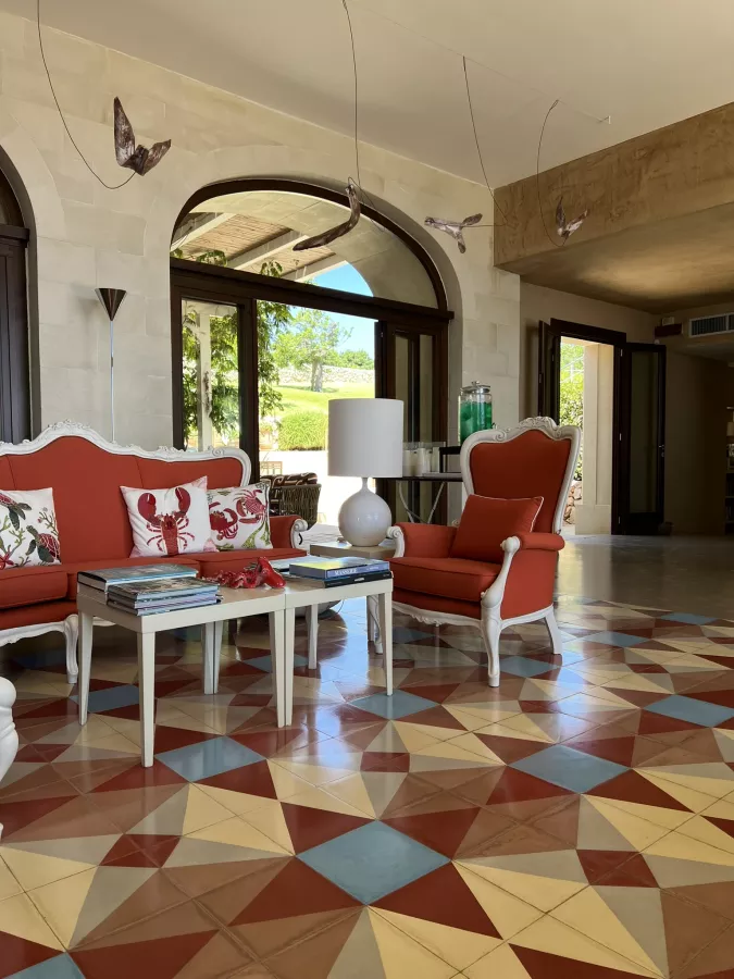 Indoor lobby with patterned floor and cushioned, red chairs