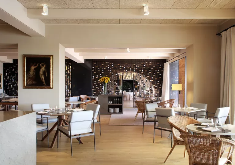 Hotel restaurant dining hall with woven chairs and square and circular tables