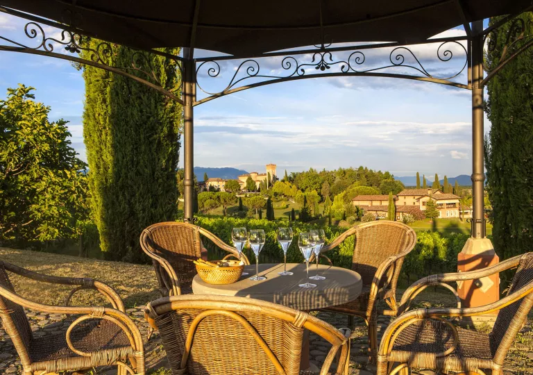 Outdoor patio with woven chairs and tables, looking out to a valley