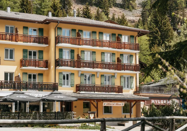 The exterior of Hôtel du Glacier, known for its yellow facade and green shutters.