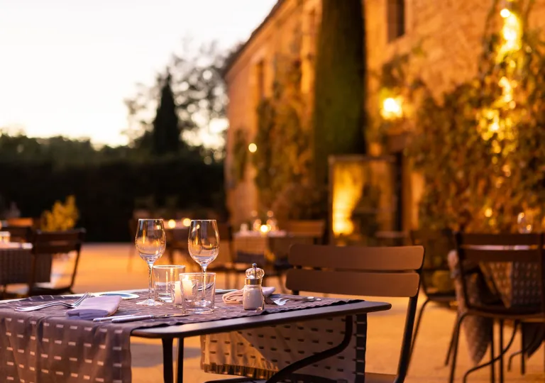Outdoor patio with dimly lit lights, and metal tables in front