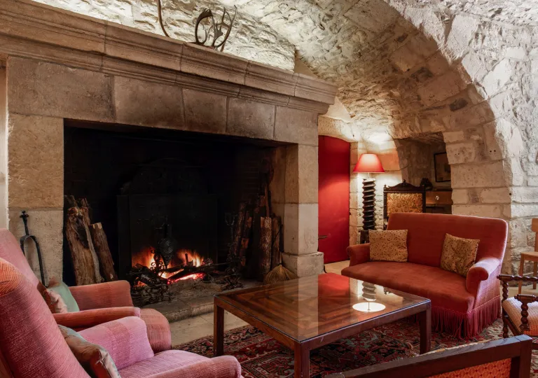 Lounge seating at Manoir d'Hautegente features red sofas, a stone fireplace, and a vaulted ceiling.