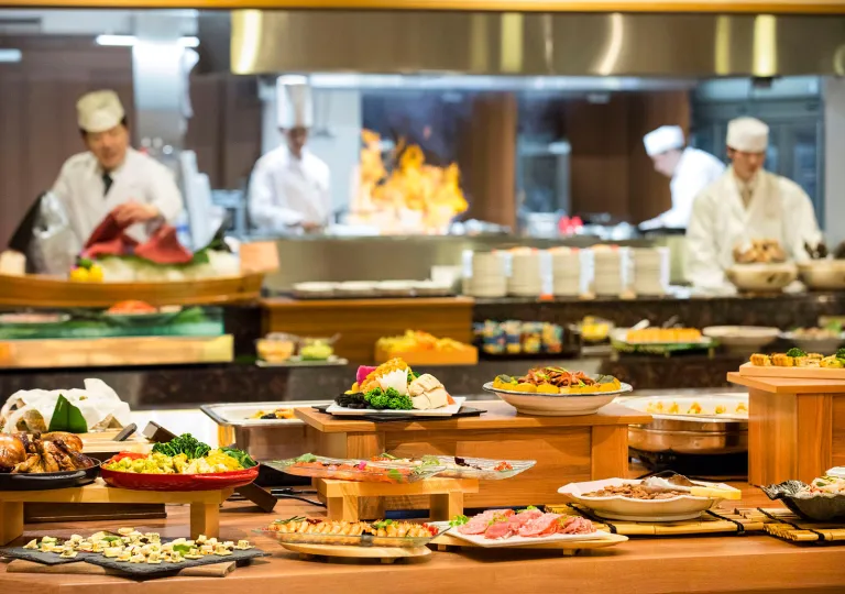 Buffet style tables with plates of food and 4 chefs in the background