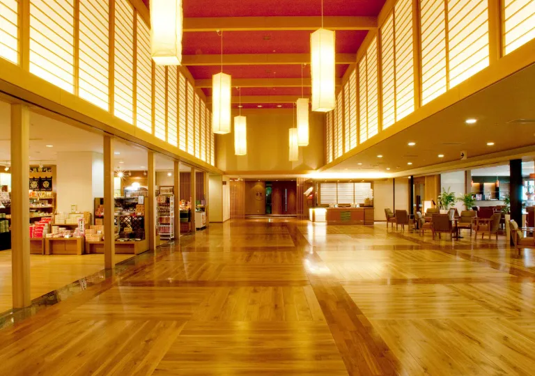 Hotel lobby area with wooden flooring and long lamps hanging from the ceiling