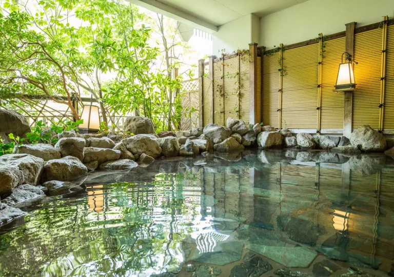 Outdoor hot tub bath surrounded by large rocks and bamboo plants