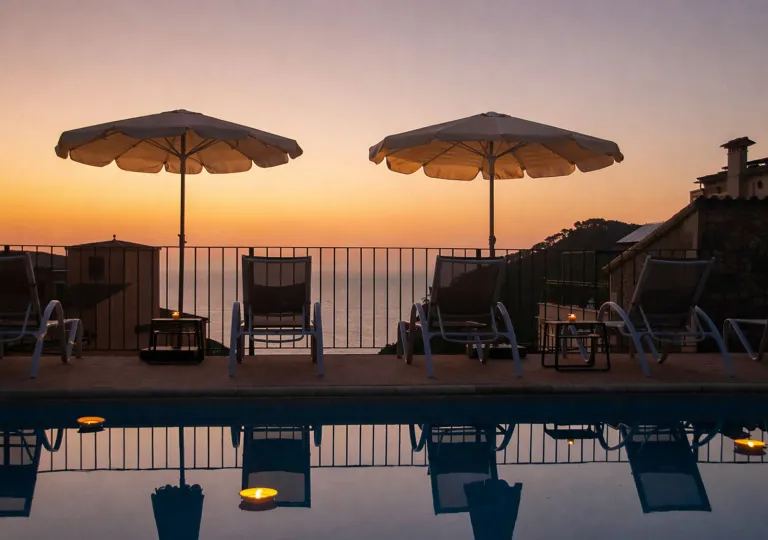 Outdoor pool with umbrellas and reclining chairs, with the sunset in the distance