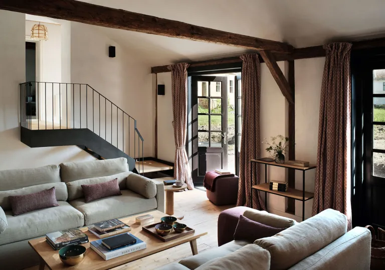 Living room area with gray sofas and a black staircase in the back