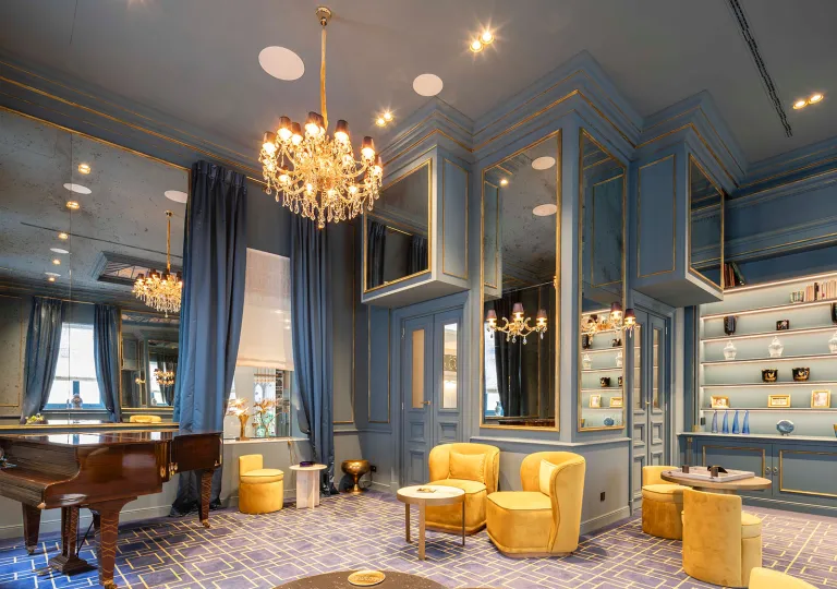 Lounge area with cushioned chairs and circular tables, in a sky blue room