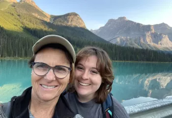 Mom and daughter smiling in front of a large lake