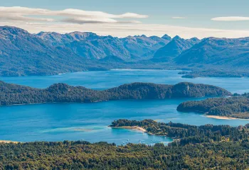 Sky view of a large lake, surrounded by tall mountains and trees