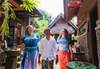 Two men and one woman smiling while walking through an alleyway of houses