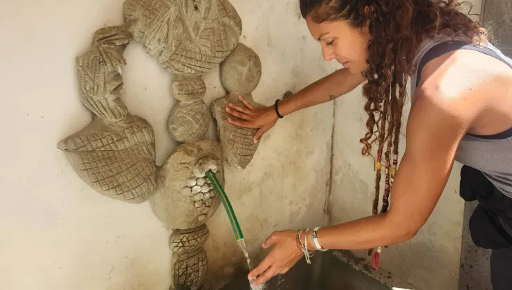Woman touching water from a stone water fountain