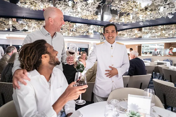 Guests dining on board a cruise ship and toasting with the captain