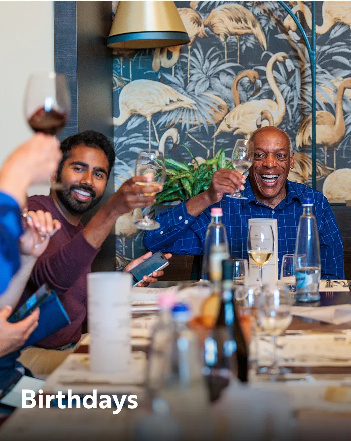 Group of people sitting around a table raising their glasses