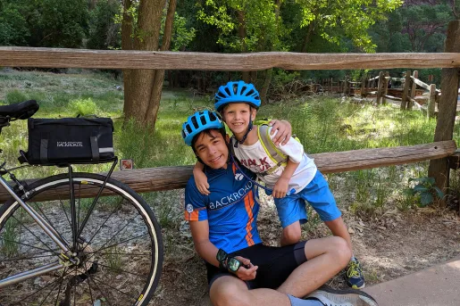 Two young guests in bike gear leaning on fence, bike beside them.