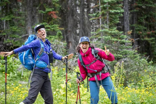 Two guests in hiking gear, posing for camera among forest.