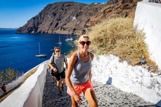 Group of guests walking up stone stairs, ocean, cliffs behind them. 