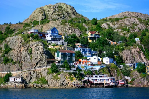 Wide shot of colorful coastal town in hillside. water below.